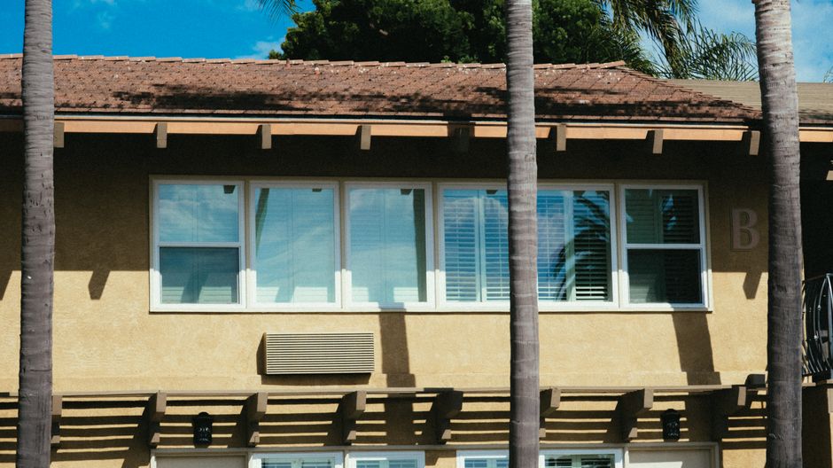 A modern house front with large windows under a clear sky.